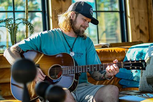 Brian Kelley playing the guitar at his home in Grayton